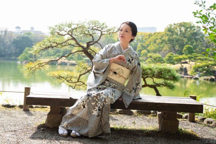 桜川舞、東京都・清澄庭園の池のそばにある木のベンチに座り、着物姿でポーズをとる