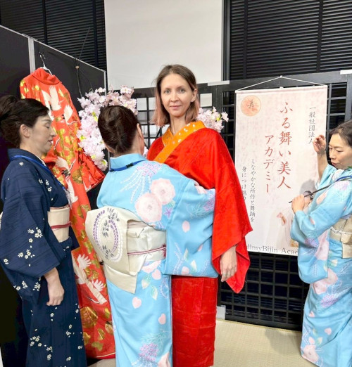 着物を着付けてもらっているアメリカ人女性の写真